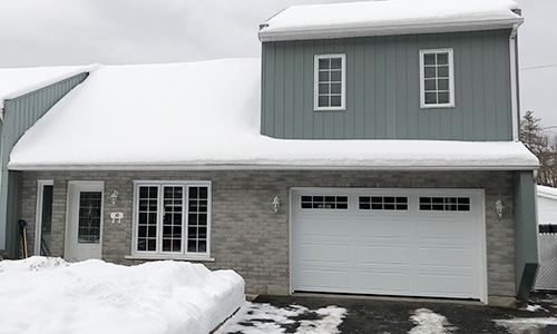 Gray house with North Hatley LP garage door, 12' x 7, Ice White, 8 lite Orion windows